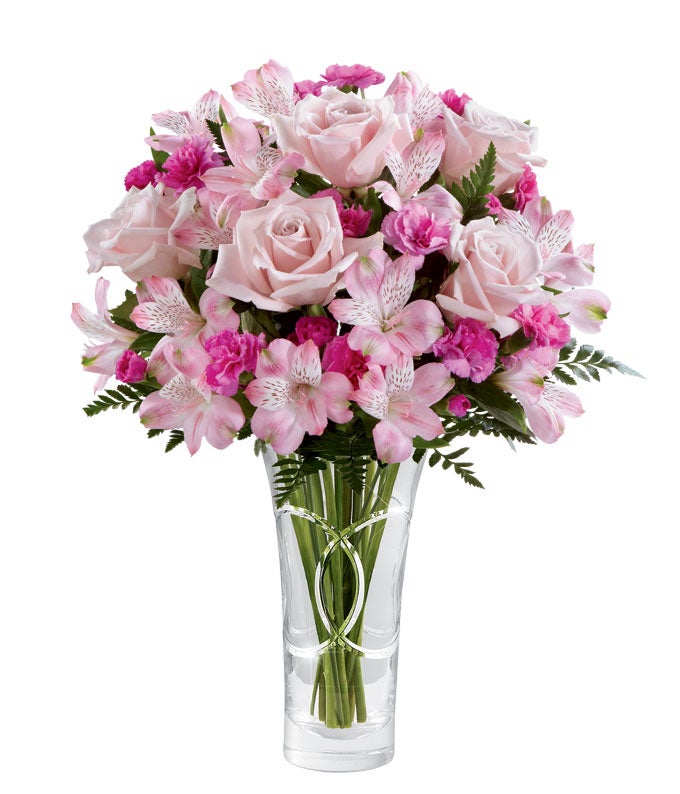 A Bouquet of Pink Roses, Hot Pink Mini Carnations, Blush Peruvian Lilies, and Fresh Greens in a clear glass vase