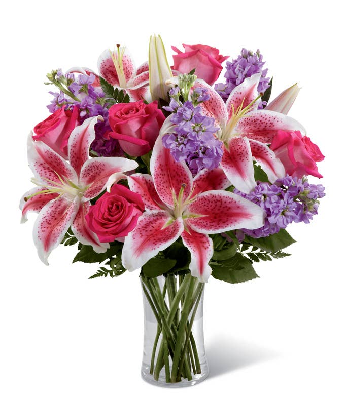 A Bouquet of Hot Pink Roses, Pink Stargazer Lilies and Light-Purple Stock in a Cylinder Vase