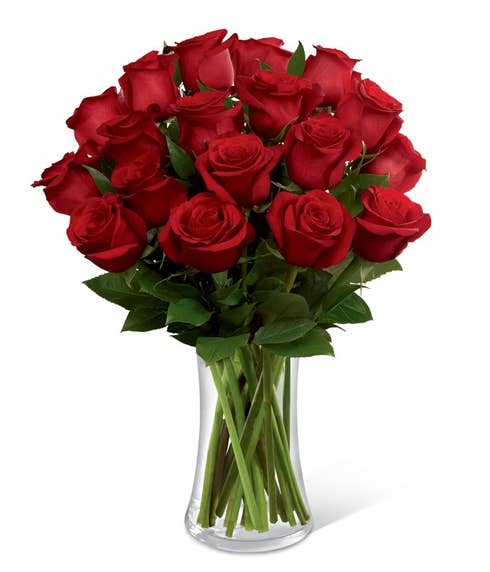 Red valentines day roses arranged by a florist in a clear swirl vase