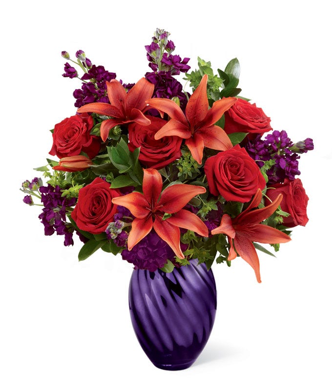 Red asiatic lily and rose flower bouquet in a glass purple vase flower delivery