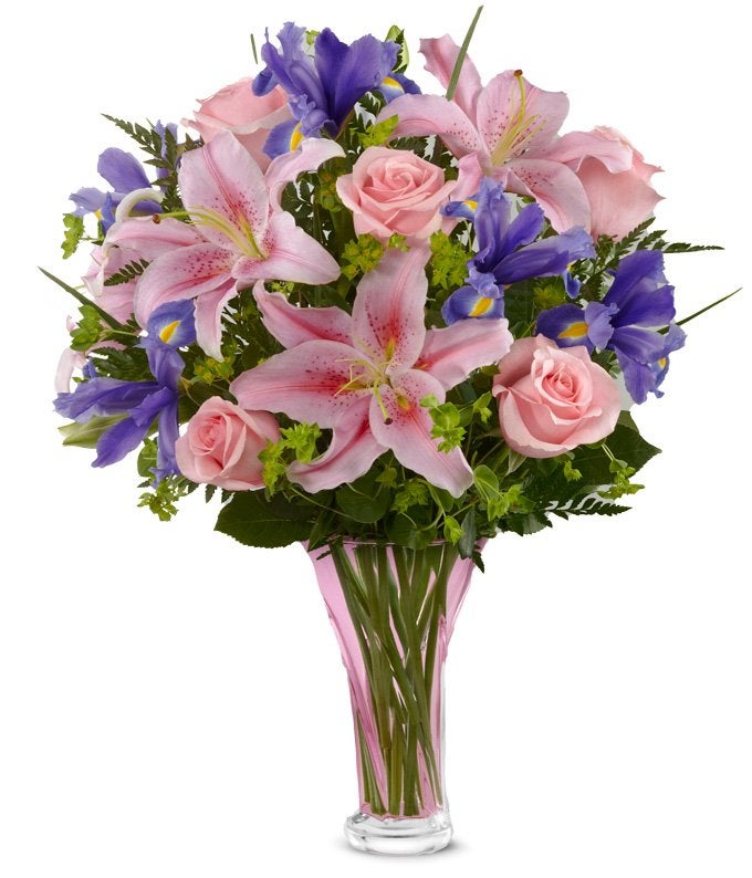 Pink lilies and blue flowers in clear vase