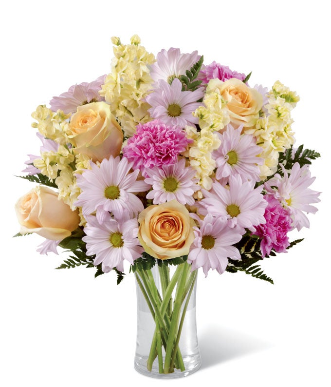 A Bouquet of Peach Roses, Lavender Daisies, Fuchsia Carnations, and Pale Yellow Stock in a Designer Clear Glass Vase