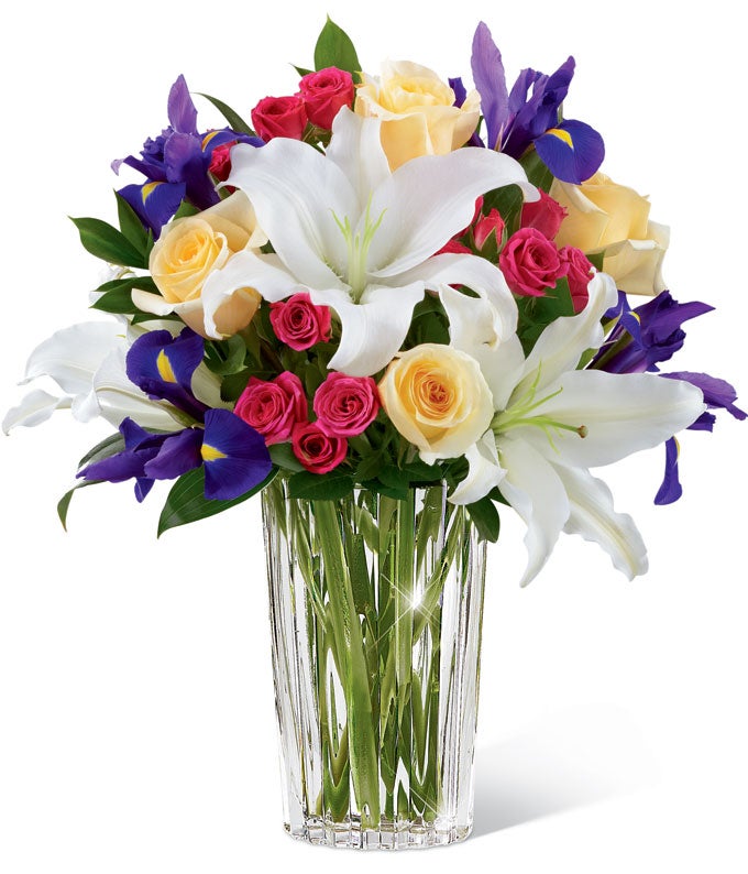 A Bouquet of  Ivory Oriental Lilies, Purple Irises and Hot Pink Spray Roses in a Modern Glass Vase