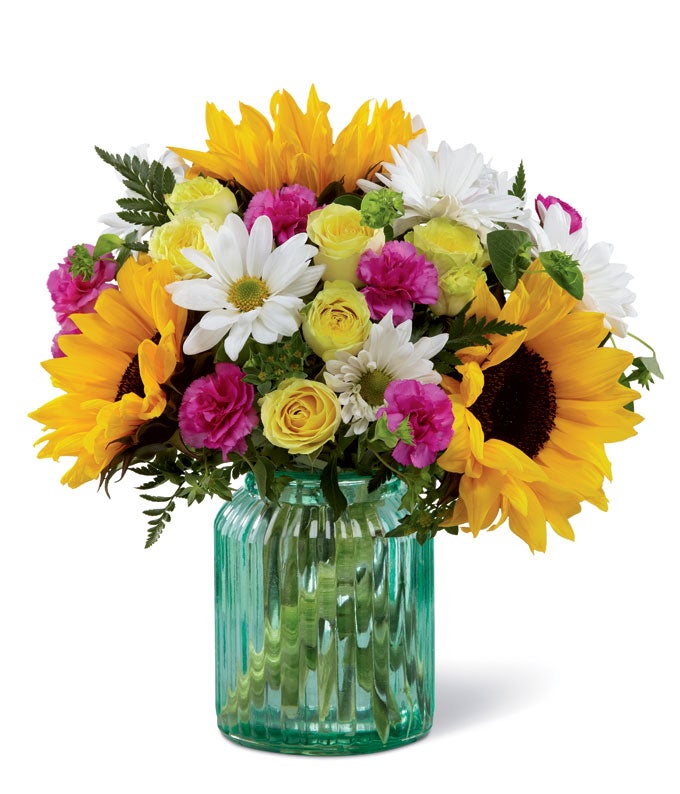 A Bouquet of  Sunflowers, Yellow Spray Roses, Magenta Mini Carnations and White Daisies in a Blue Canister Glass Vase