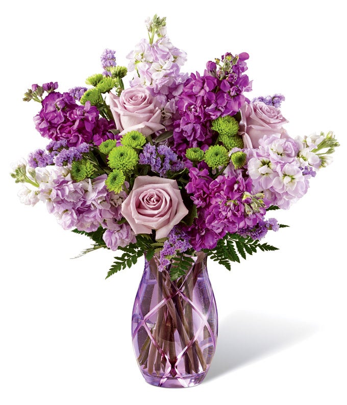 A Bouquet of Amethyst Roses, Light Purple Gilly, Violet Statice, Green Button Poms, and Lush Greens in a Glass Vase