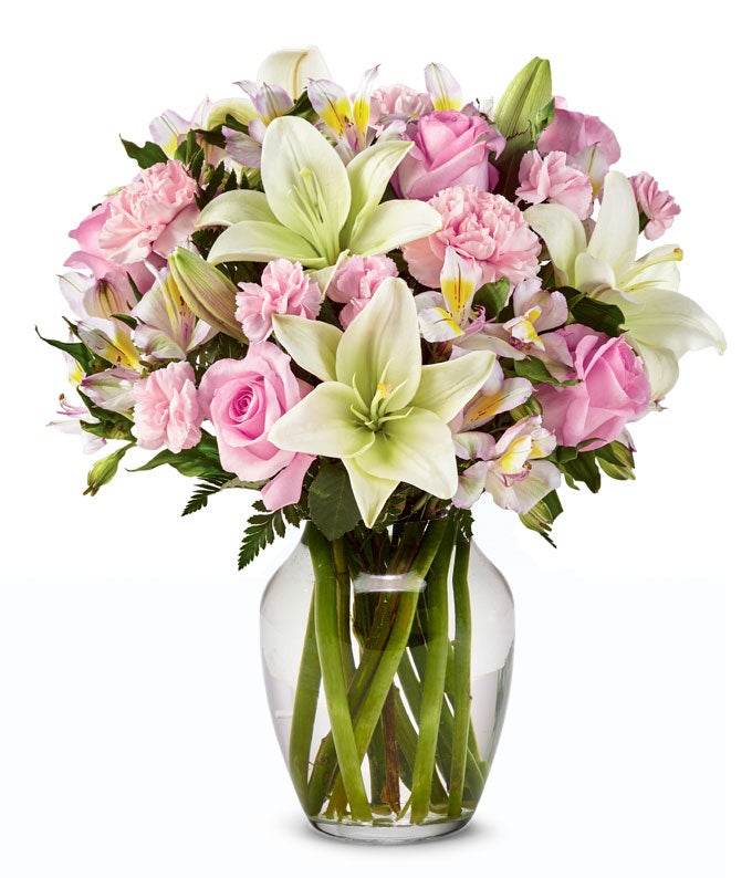 A Bouquet of  Pale Roses, Blush Full and Mini Carnations, Ivory Asiatic Lilies, and Peruvian Lilies in a Glass Vase
