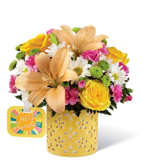 Light orange lily, white daisy, and yellow rose bouquet in a clear glass vase