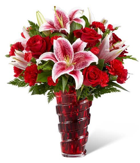 Red stargazer lilies, red roses and green filler in a red vase