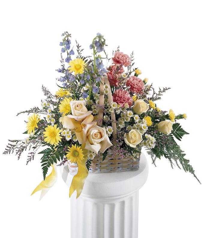 A Bouquet of Pink, yellow, and soft blue flowers in a Basket