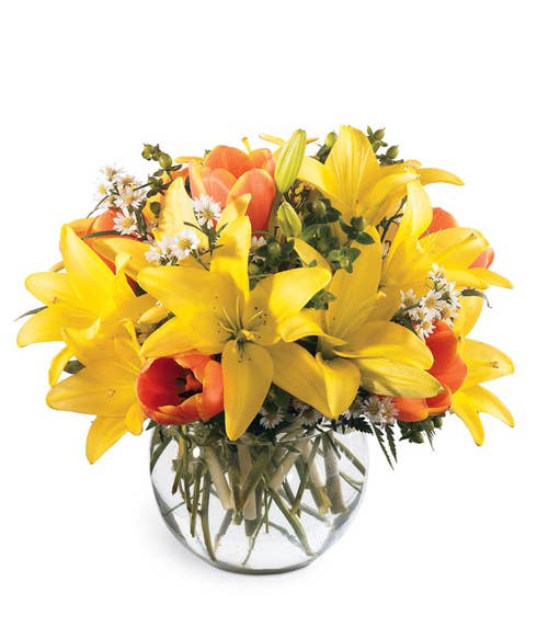 Yellow lily and orange tulip bouquet in a glass bubble bowl