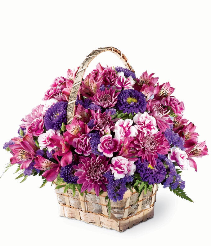 A Bouquet of Purple Alstroemeria, Variegated Purple Mini Carnations, Purple Cushion Poms, Deep Purple Statice, and Deep Purple Matsumoto Asters in a Birchbark Handled Basket