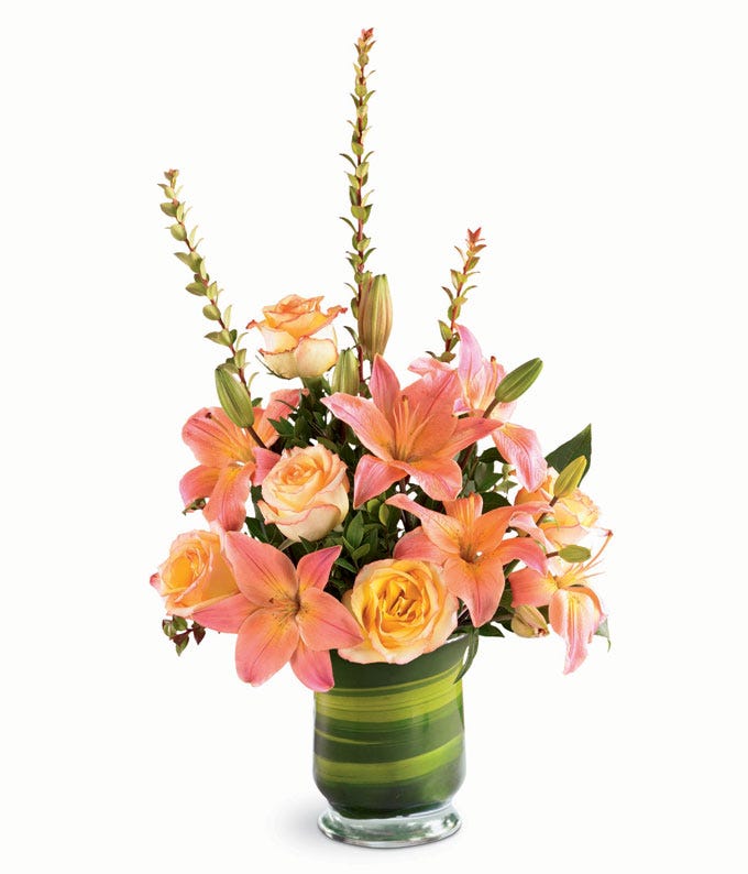 Orange lilies are arranged with lilies and ti leaves