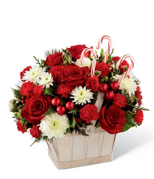 Red and white flowers delivered in a basket with mini ornaments and candy cane