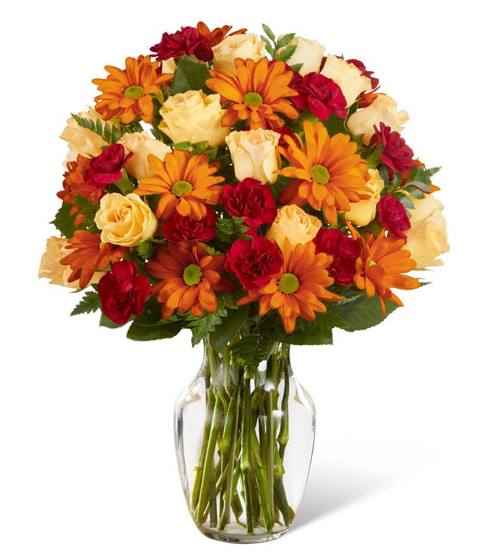A Bouquet of Peach Spray Roses, Burgundy Mini Carnations, and Butterscotch Daisy Poms with Decorative Ribbon in a Glass Vase