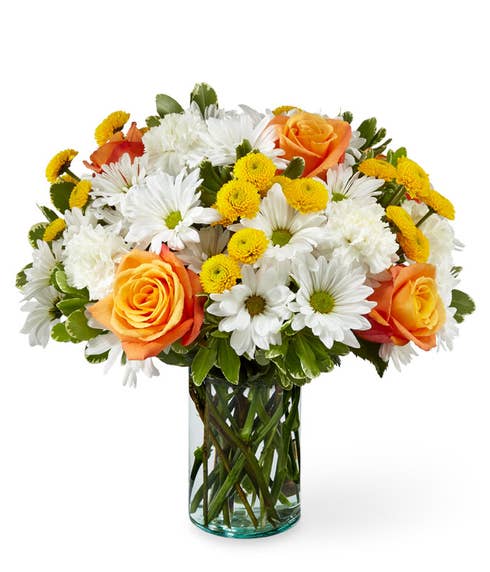 Orange rose white daisy and yellow button pom flower bouquet in a clear vase