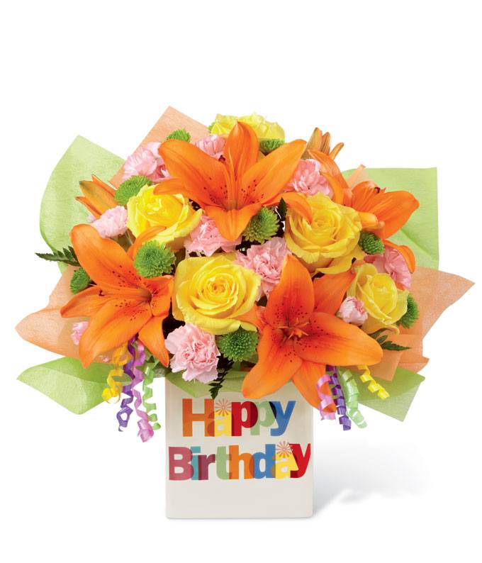A Bouquet of  Yellow Roses, Orange Asiatic Lilies, Pink Mini Carnations, and Green Button Poms in a Ceramic Happy Birthday Vase