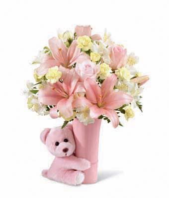 Pastel pink roses, pale yellow mini carnations, white Peruvian lilies, pink Asiatic lilies and a variety of greens in a pink ceramic vase
