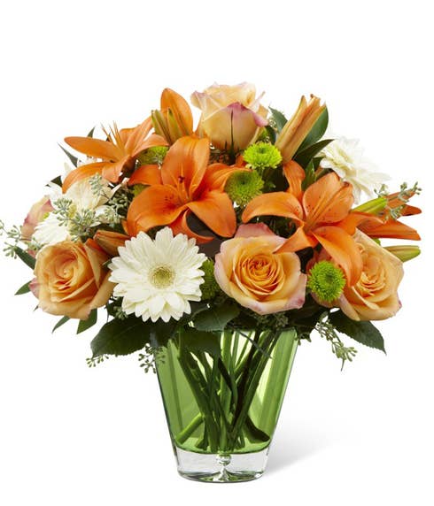 Peach roses, white gerbera daisies, green button poms in a glass vase
