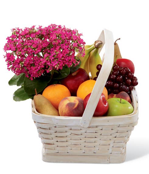 A hot pink kalanchoe plant in a large whitewash woodchip handled basket filled with an assortment of fruit