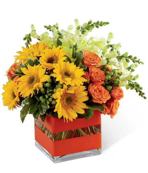 A floral combination of mini sunflowers, orange spray roses, yellow snapdragons, and green hypericum berries