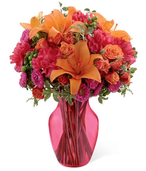 Floral arrangement of orange spray roses, orange Asiatic lilies, hot pink matsumoto asters, fuchsia carnations, and green hypericum berries