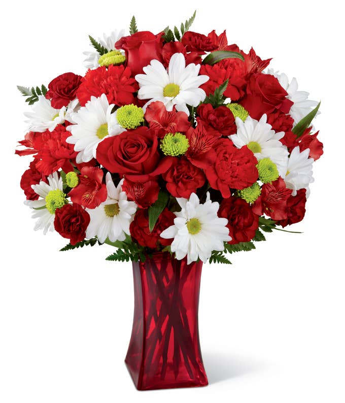 A Bouquet of Red Roses, White Daisy Poms, Mini Burgundy Carnations, Scarlet Alstroemerias, Green Button Poms and Leatherleaf in a Ruby Hued Glass Vase