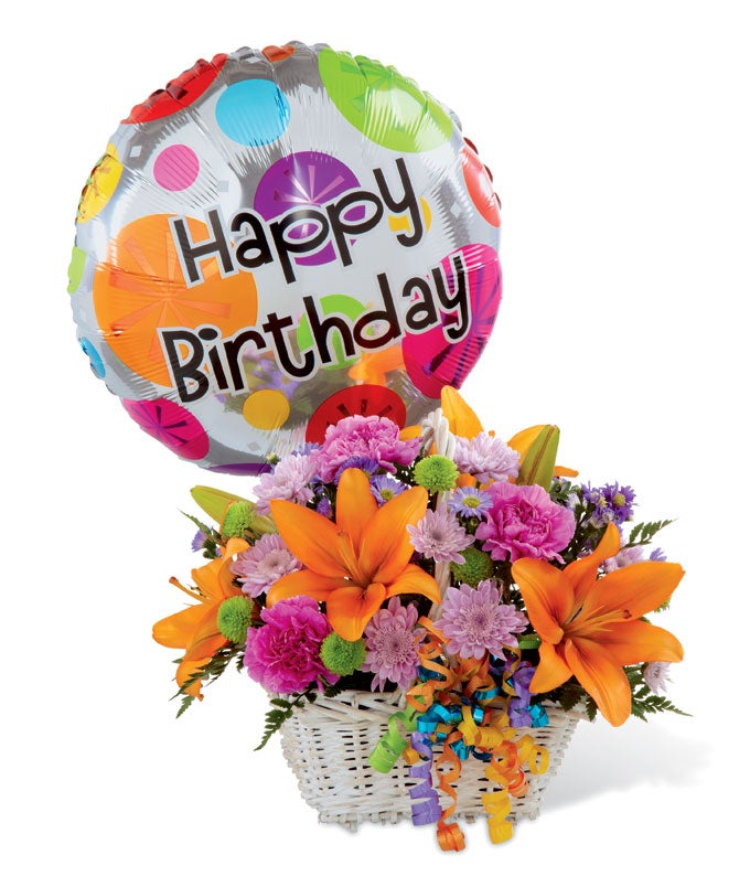 A bouquet of Orange Asiatic Lilies, Purple Carnations, and Green Button Poms on a white basket with curly ribbon and 1 round Happy Birthday Balloon