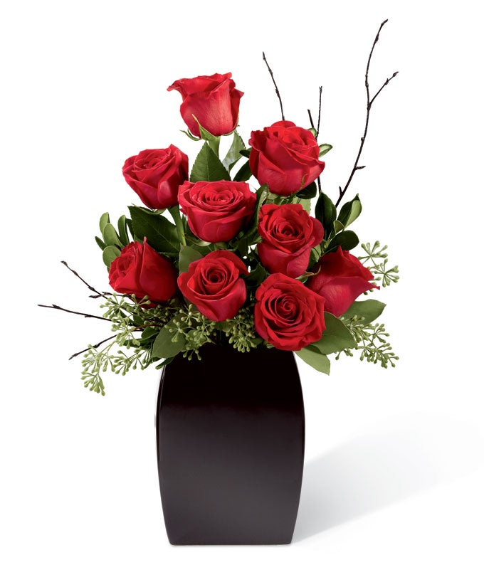 A Bouquet of  Red Roses, Lush Greens,  and Black Painted Branches in a Black Ceramic Vase