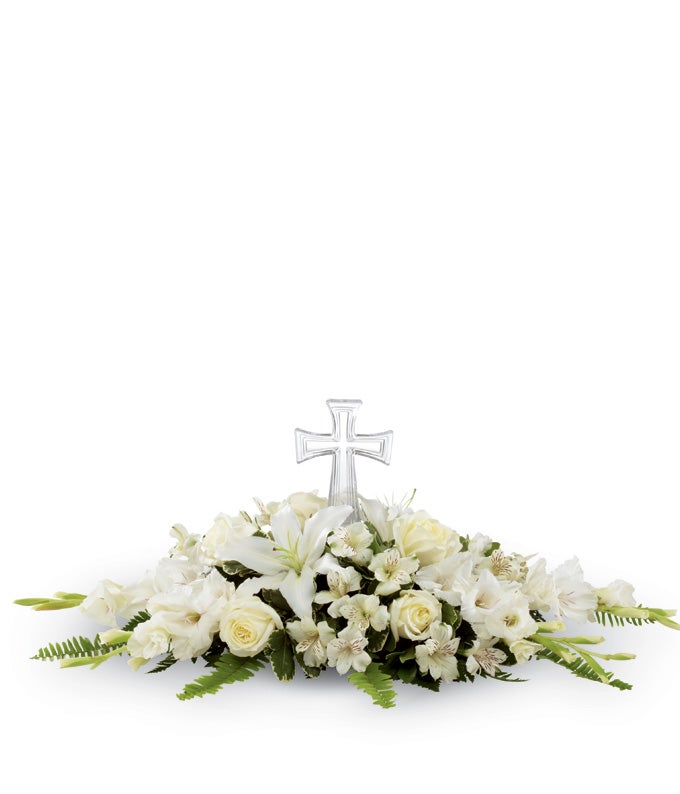 A centerpiece arrangement of flowers that include White Roses, White Gladiolus, White Peruvian Lilies, White Oriental Lilies and Boston Fern Fronds with Elegant Cross