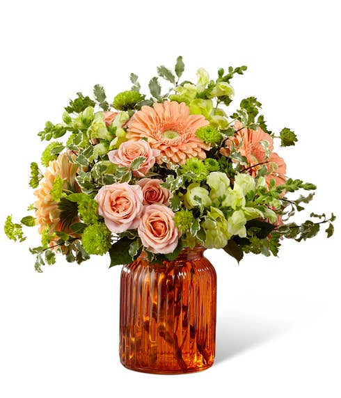 Pastel orange gerbera daisies with orange spray roses in an orange vase