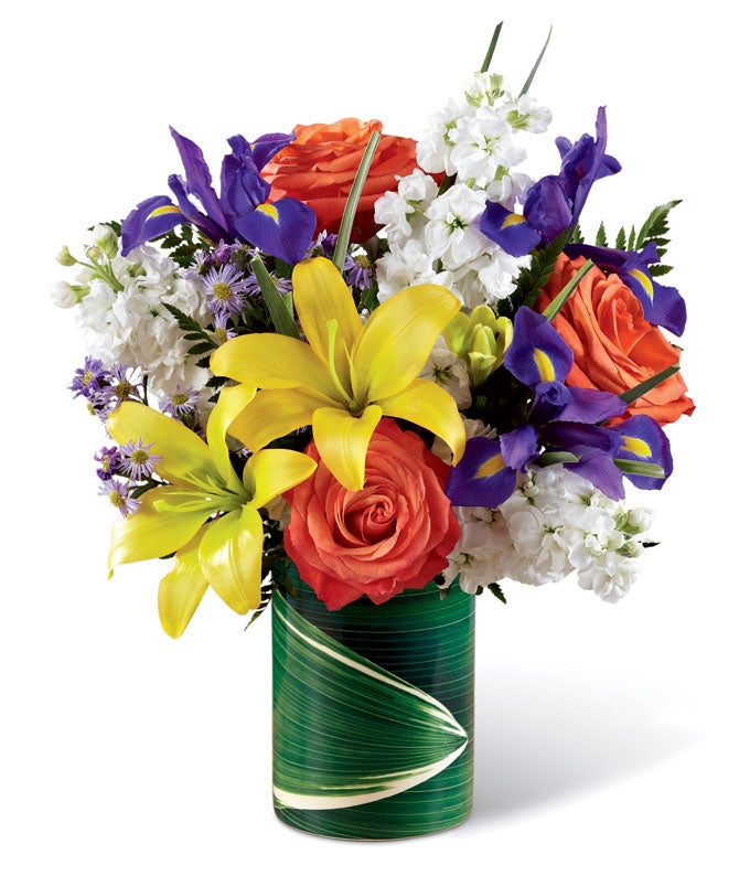 A Bouquet of Blue Iris, White Stock, Yellow Lilies, and Orange Roses in a Leaf Vase