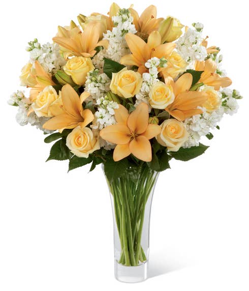 Cream roses, peach lilies, and white stock in a premium flower bouquet