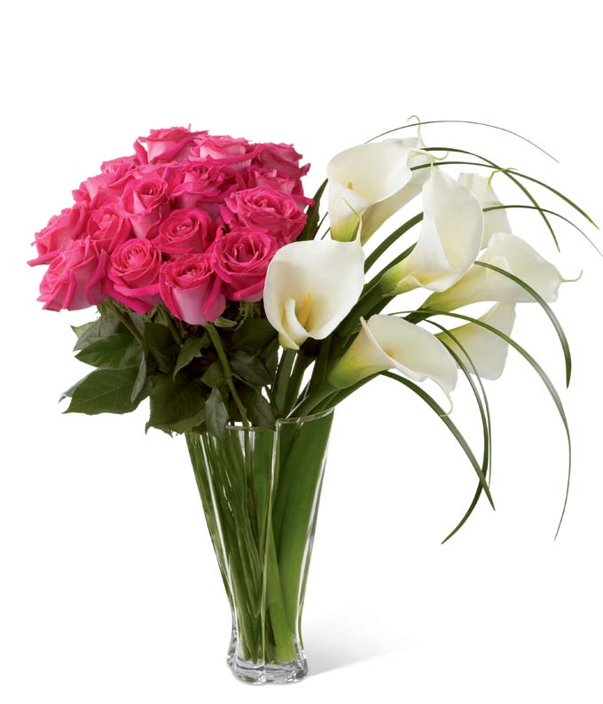 Fuchsia roses, open-cut calla lilies, and lily grass blades in a superior clear glass twist vase
