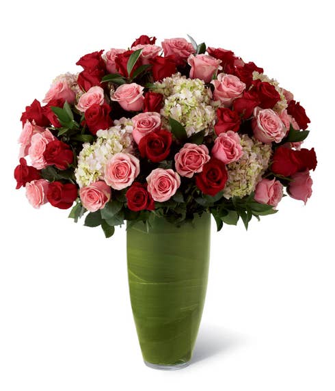 Premium long-stemmed red roses, premium long-stemmed pink roses, pink hydrangea, lush greens, and exotic foliage in a superior 14-inch clear glass bullet vase