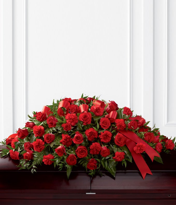 Casket Spray Including Red Roses, Red Carnations, and Seasonal Greens with Decorative Ribbon