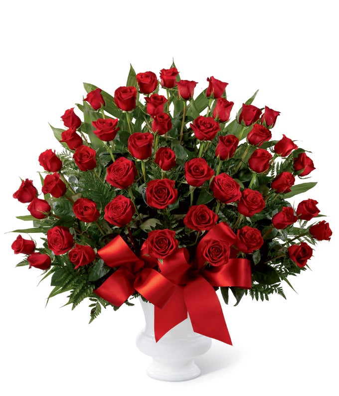 A Bouquet of  Red Roses and Seasonal Green in a Decorative Urn with Red Ribbon