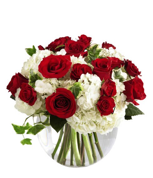 Red roses, white hydrangea and red spray roses in circular glass vase
