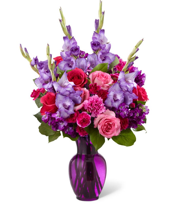 A Bouquet of  Dark Purple Gladiolus, Pink Roses, Hot Pink Carnations, and Light-Purple Stock in a Deep Purple Glass Vase