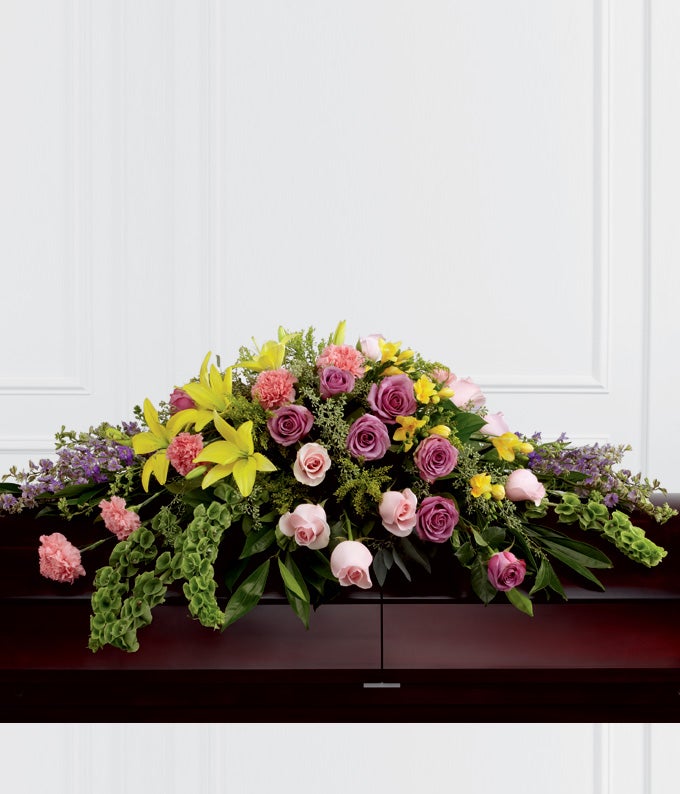 Casket Spray Including Lavender Roses, Pink Roses, Lavender Larkspur, Pink Carnations, Bells of Ireland, Yellow Asiatic Lilies and Yellow Freesia