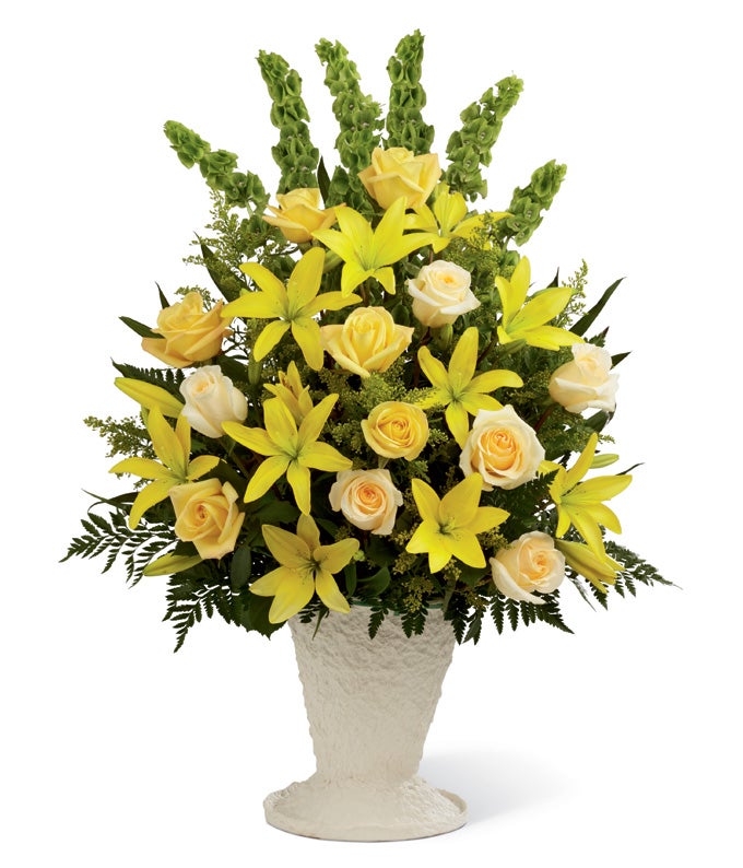 A Bouquet of Yellow Asiatic Lilies, Yellow Lilies, Cream Roses, Bells of Ireland, Palm & Greens in a Keepsake Floral Container