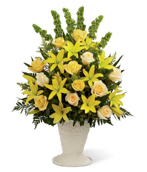 Yellow lilies and cream roses in container for sympathy gift