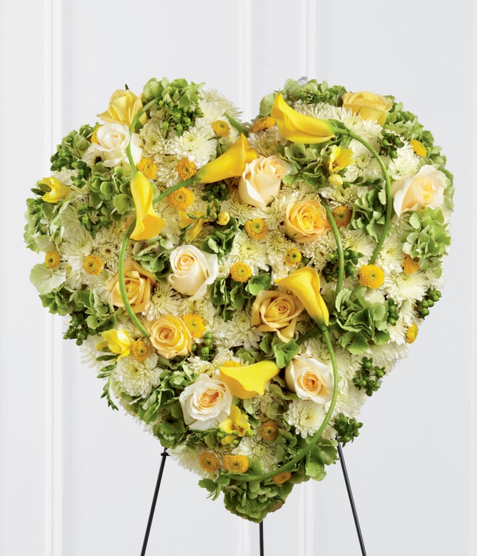 Heart-Shaped  Flower arrangement including Yellow Roses, Straw Colored Freesia, Yellow Mini Calla Lilies, Gold Button Poms, Green Hydrangea, Cream Roses, White Chrysanthemums, and Hypericum Berries with Stand Included