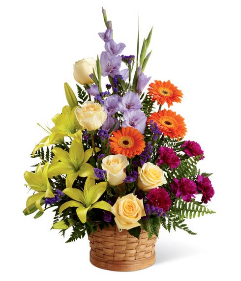 Yellow roses, yellow asiaitic lilies and purple flowers in a funeral floral basket