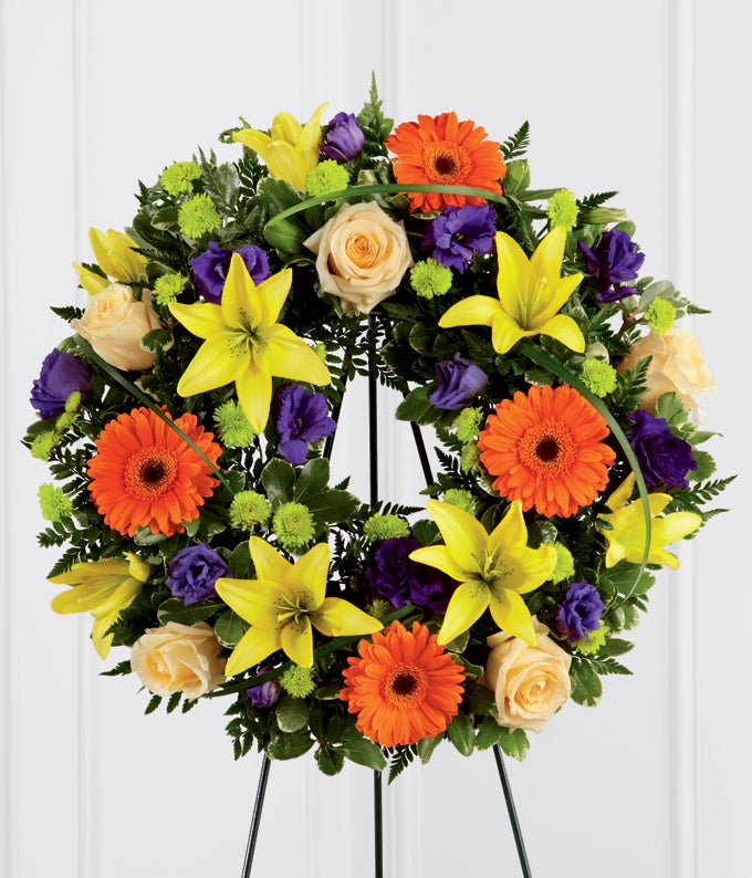 Round Flower arrangement including Creme de la Creme Roses, Purple Lisianthus, Orange Gerbera Daisies, Yellow Asiatic Lilies, and Green Button Poms with Stand Included