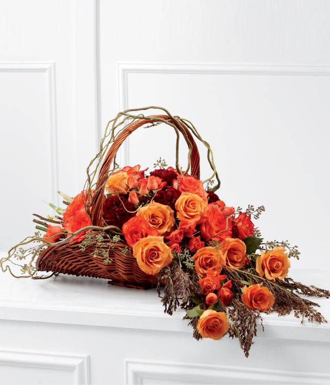 A Bouquet of Burnt-Orange Roses, Bi-colored Orange Roses, Burgundy Carnations and Apricot Spray Roses in a Willow Fireside Basket With Handle