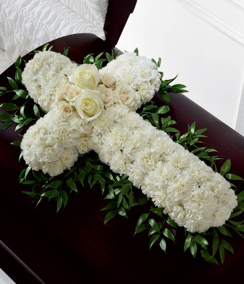 White spray roses or carnations arranged in a sympathy cross