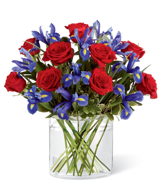 A Bouquet of Red Roses, Dark Purple Irises and Ruscus in an Oblong Glass Vase with Card Message