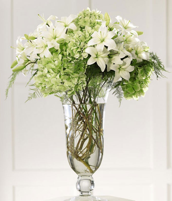 A Bouquet of White Asiatic Lilies, Green Hydrangea, and Curly Willow in a Clear Glass Trumpet Vase