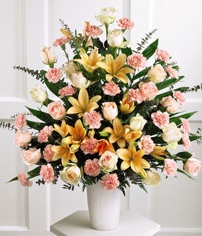 A Bouquet of Peach Roses, Pink Carnations, Peach Asiatic Lilies and Baby Blue Eucalyptus in a White Ceramic Vase
