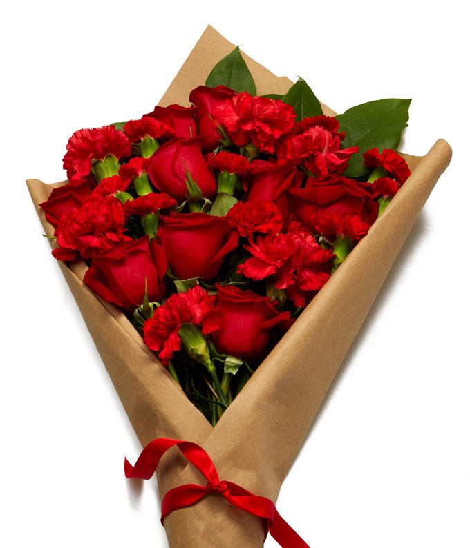 A Bouquet of Red Roses, Scarlet Carnations and Fresh Greens Wrapped Within Parchment Paper with Crimson Colored Bow